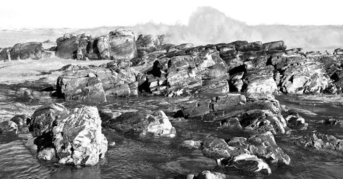 Panoramic view of rocks on shore against sky