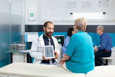 Physiotherapist showing human skeleton to patient in clinic