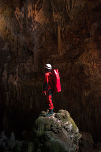 Rear view of man standing on rock in cave