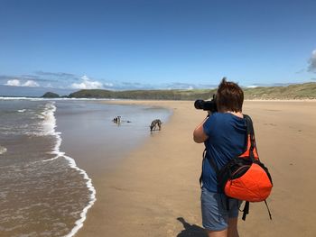 Rear view of man standing on beach against clear sky