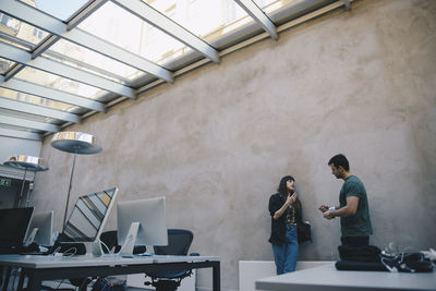 Low angle view of computer programmers discussing against wall in office