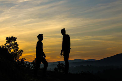 Silhouette friends standing against sky during sunset