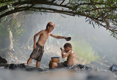 Boy bathing brother in forest