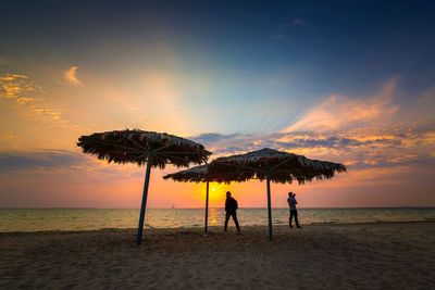 Silhouette people on beach against sky during sunset