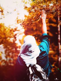 Rear view of man with autumn leaves in park