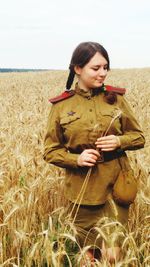 Young woman standing on field against sky