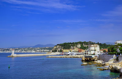 Buildings by sea against blue sky