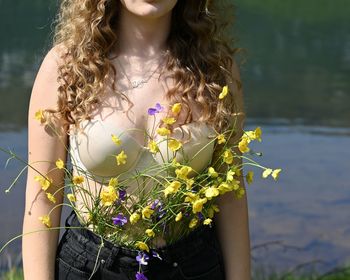 Midsection of woman standing by flowering plants