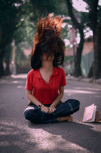 Woman tossing hair while sitting on road