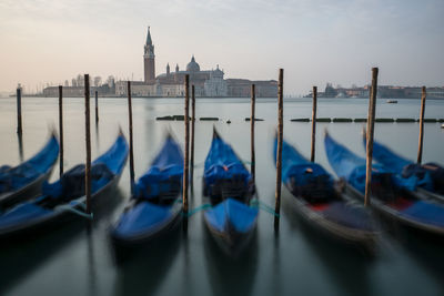 Gondolas moored on lake with church of san giorgio maggiore on background