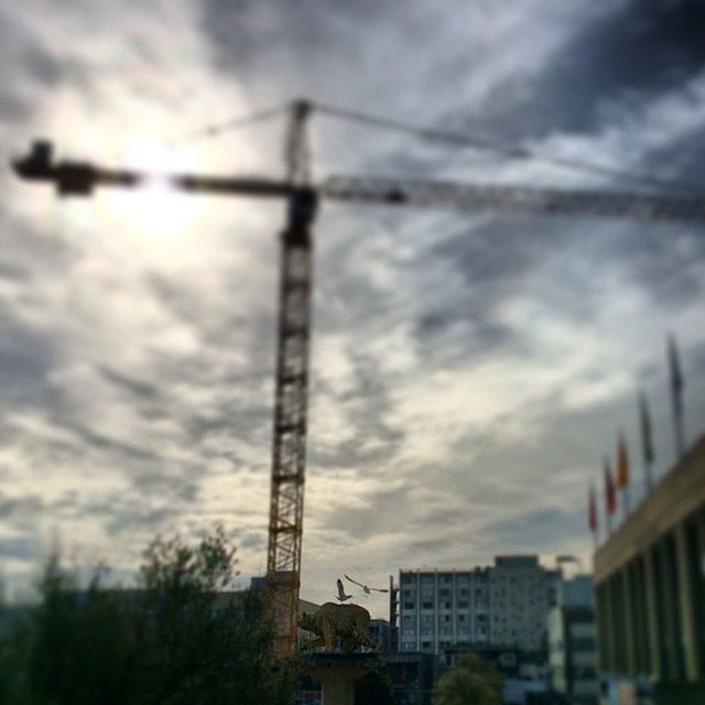 sky, architecture, built structure, low angle view, cloud - sky, building exterior, cloudy, fuel and power generation, connection, power line, technology, cloud, cable, electricity pylon, crane - construction machinery, electricity, silhouette, outdoors, overcast, power supply