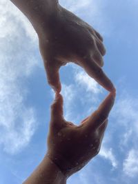 Low angle view of human hand against sky