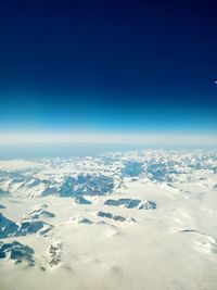 Aerial view of snowcapped landscape against blue sky