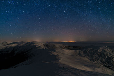 Scenic view of snowcapped mountains against sky at night