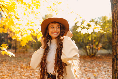 Portrait of young woman wearing hat standing on field
