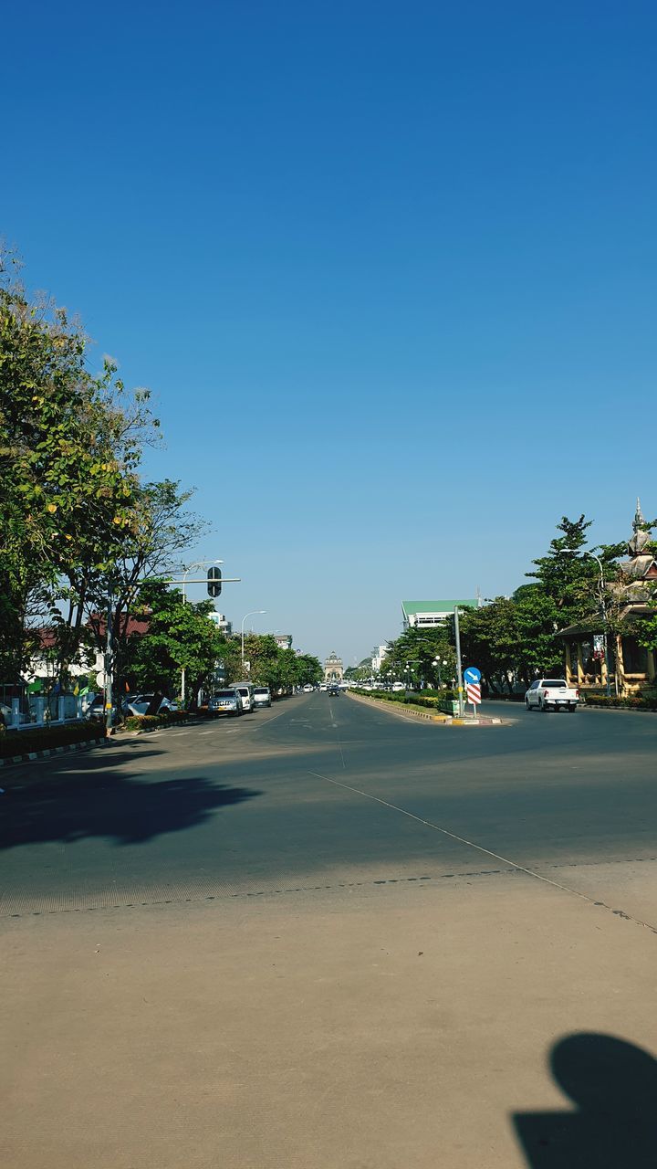 tree, sky, nature, plant, transportation, clear sky, blue, sunlight, shadow, road, city, day, beach, sunny, sea, land, vacation, architecture, street, no people, outdoors, horizon, travel, travel destinations, car, copy space, motor vehicle, water, coast, mode of transportation, sand, built structure, palm tree, tropical climate