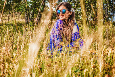 Portrait of smiling young woman wearing sunglasses on field