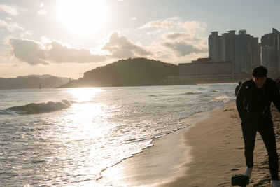 Rear view of man at beach during sunset