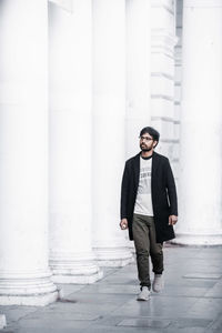 Young man looking away while standing against building