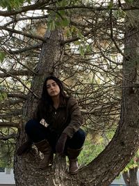 Portrait of young woman sitting on tree trunk