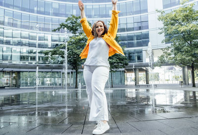 Confident plus size curvy happy young woman dancing street fountains modern background.