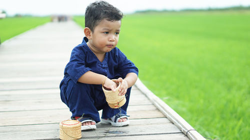 Boy looking away crouching on boardwalk