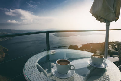 Close-up of coffee on table by sea against sky