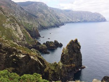 Scenic view of sea by mountains against sky