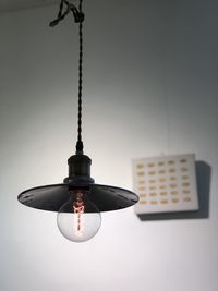 Low angle view of illuminated lamp hanging against ceiling
