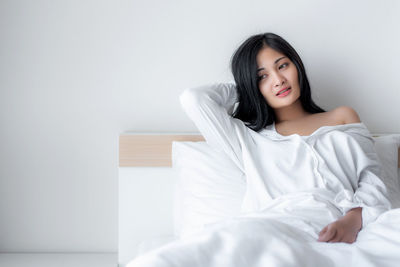 Portrait of woman sitting on bed at home