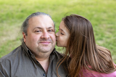 Daughter kisses her father in the park. father's day. happy daughter kisses her father. 