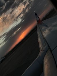 Airplane flying over sea against sky during sunset
