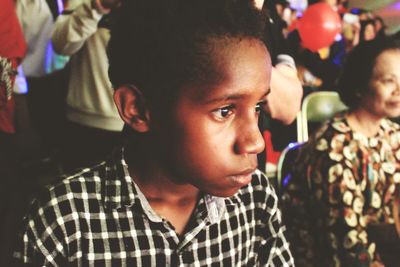 Close-up of serious boy looking away while sitting in event