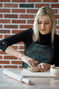 Young woman making face while sitting on table