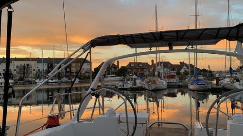 Sailboats moored at harbor during sunset