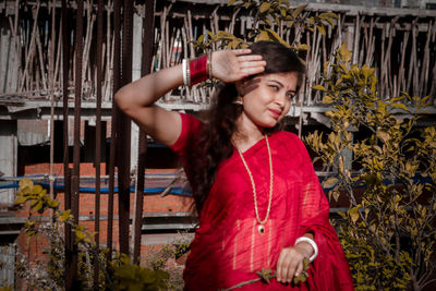 Portrait of beautiful young woman standing against plants