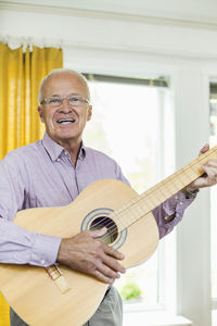 Portrait of happy man playing guitar at home