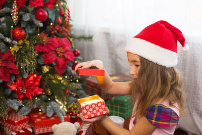 Rear view of girl holding christmas tree in box