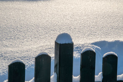 Wooden posts on snow covered fence