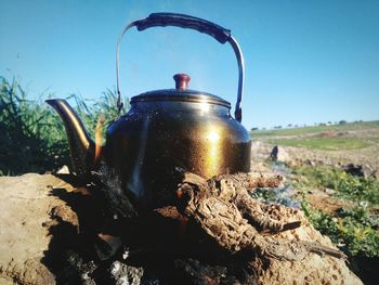 Close-up of kettle on land against clear sky during sunny day