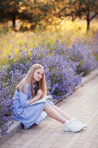Girl sitting in park in flowers. education learning concept  happy student  doing homework