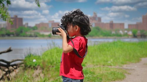 Side view of child photographing with camera