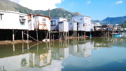 Reflection of houses in lake against sky