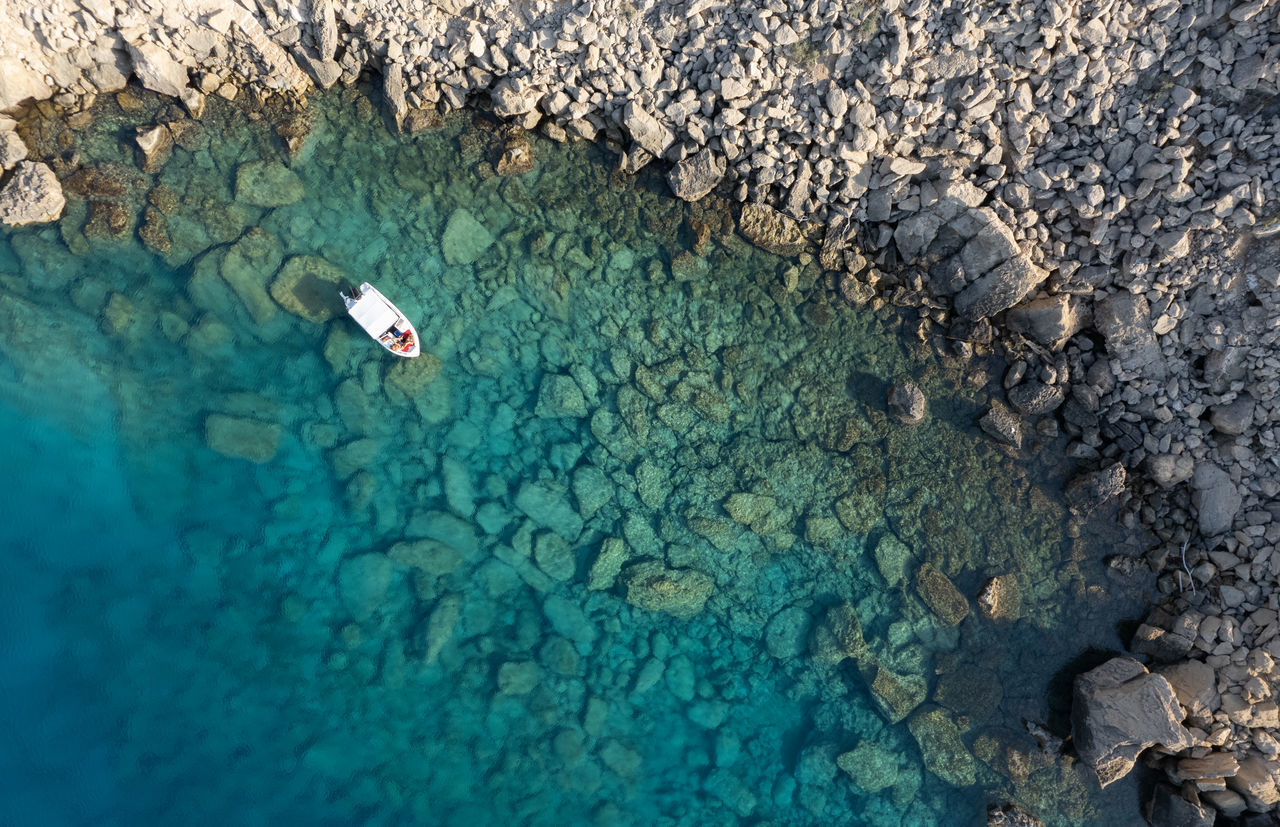 HIGH ANGLE VIEW OF ROCK FORMATIONS IN SEA