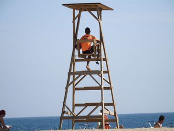 People standing on beach against clear sky