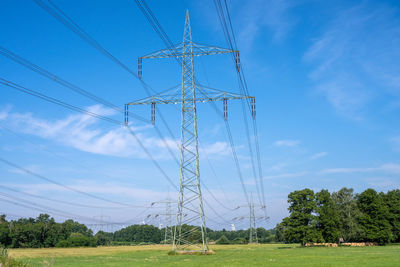 Low angle view of electricity pylon on field against sky