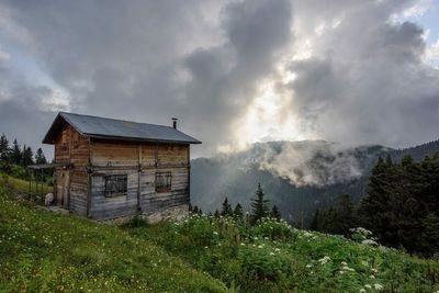 Houses on landscape against cloudy sky