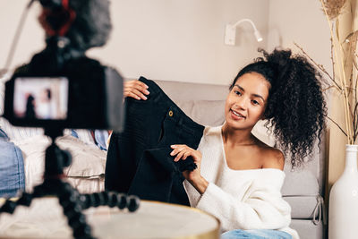 Young influencer vlogging about clothing while sitting at home