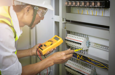 Electrical engineers test the voltage and current of the wires in the electrical cabinet control.