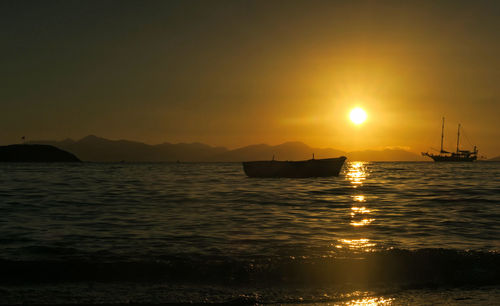 Silhouette boat in sea against sky during sunset